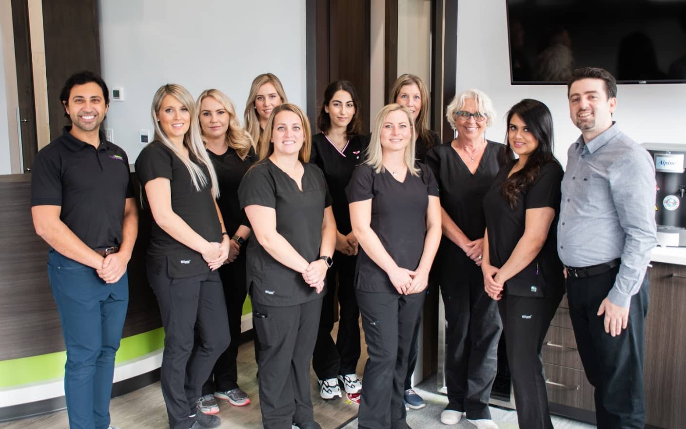 Group photo of 11 Hometown Orthodontics team members, posing together with smiles in front of a clinic backdrop.